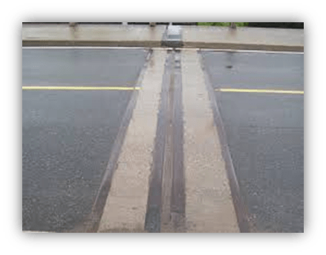 "Close-up of a rain-soaked road with a visible expansion joint."