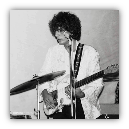 Young musician playing guitar on stage, 1960s style.