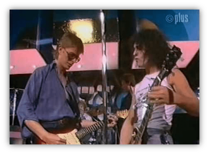 "Two musicians performing on stage with electric guitars, showcasing a live music vibe."