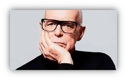 "Thoughtful man in glasses resting chin on hand, wearing a black turtleneck."
