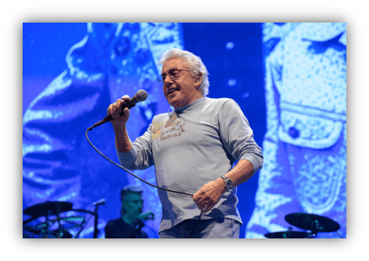Singer performing on stage with microphone in hand, vibrant background.