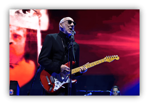 "Musician performing on stage with electric guitar and vibrant background lights."