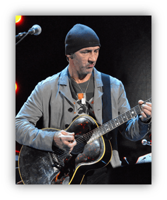 Musician playing guitar on stage, wearing a beanie and gray jacket.
