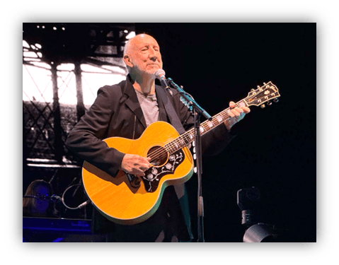 "Musician performing on stage with acoustic guitar."