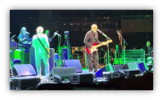 "Musicians performing on stage with guitars at a live concert."