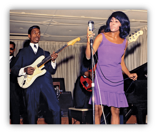 "Musical performance featuring a female singer in a purple dress and a male guitarist on stage."