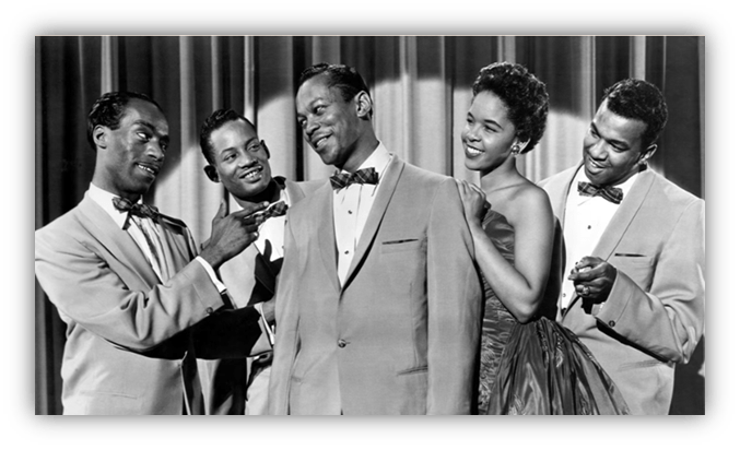 "Vintage black and white photo of five stylish singers in formal attire, posing together with cheerful expressions."