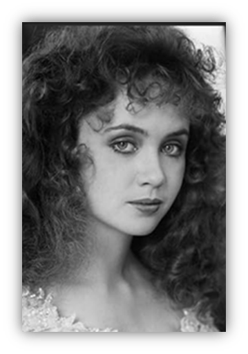 "Black and white portrait of a young woman with curly hair and striking blue eyes."
