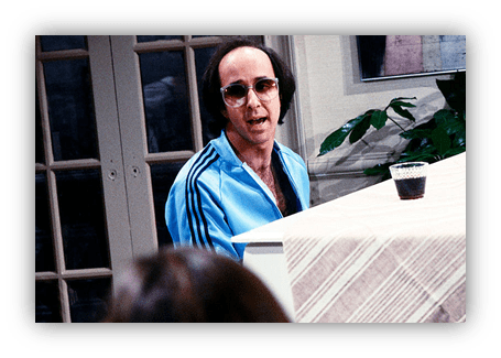 Man in sunglasses performing at a piano in a blue tracksuit.