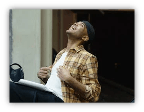 "Man laughing joyfully in casual attire, sitting in a relaxed setting."