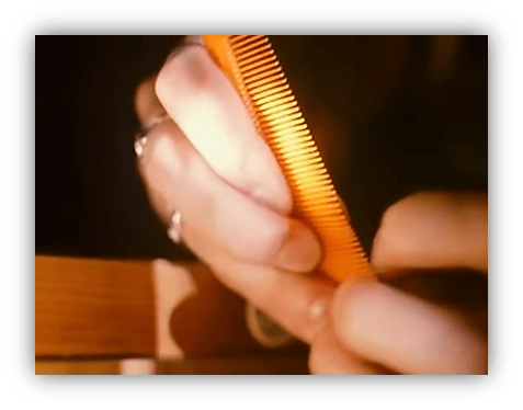 Close-up of hands holding an orange comb, focusing on hair grooming.