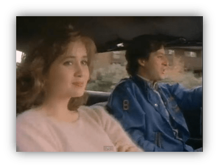 "Scene from a classic film featuring a woman and man driving in a car."