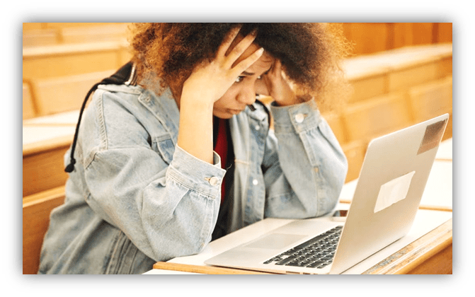 Stressed student with laptop in classroom.