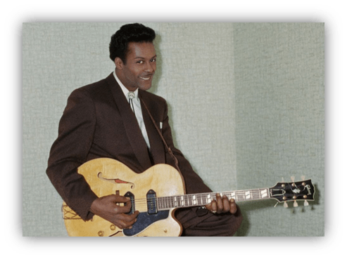 "Smiling musician in a suit playing a yellow guitar."