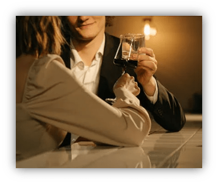 "Couple toasting with wine glasses at a bar."
