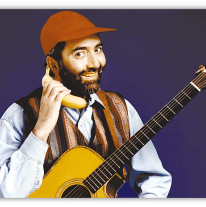 "Man in a cap holding a banana as a phone, smiling with an acoustic guitar."