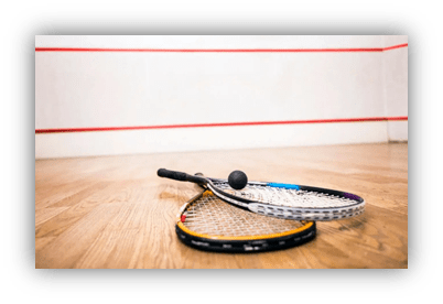 "Squash rackets and ball on wooden floor in a squash court."