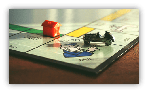 "Close-up of Monopoly game board with car and house near 'Go to Jail' space."