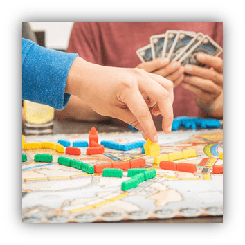 "Player placing a game piece on a colorful board with cards in hand."