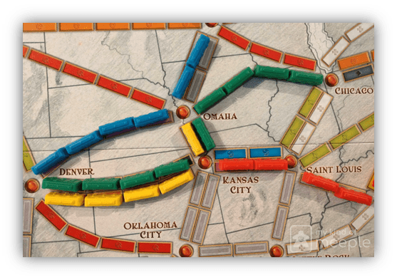 "Ticket to Ride board game with colorful train pieces connecting cities like Denver, Omaha, and Kansas City."