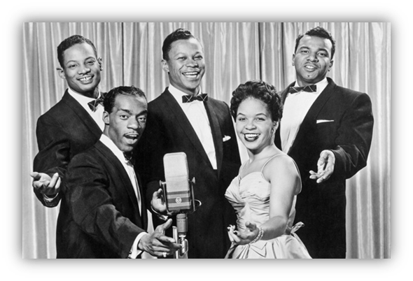 "Vintage black and white photo of a five-member vocal group, featuring a woman in a dress and four men in tuxedos, posing with a microphone."