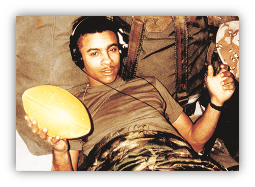 "Soldier relaxing with a football and headphones in a military setting."