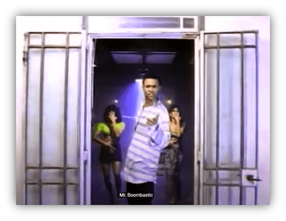 "Mr. Boombastic performing with dancers in a vibrant music video scene."