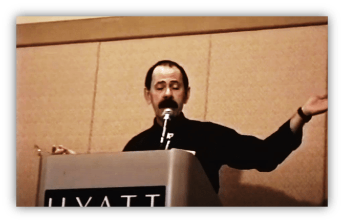 Speaker presenting at a Hyatt conference, gesturing while speaking into a microphone.