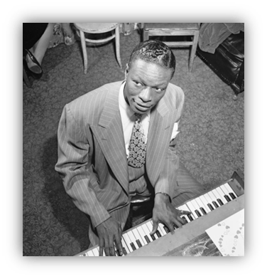"Black and white image of a man in a striped suit playing piano."
