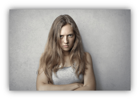 "Angry young woman with long hair against a concrete background."