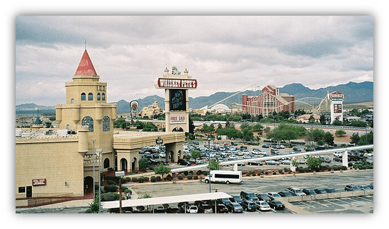"Whiskey Pete's Casino with mountain backdrop and parking lot."