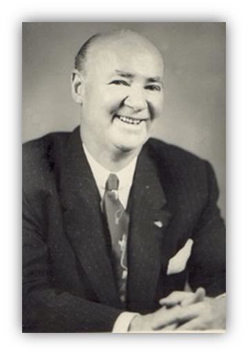"Smiling man in a suit with a tie, seated at a table."