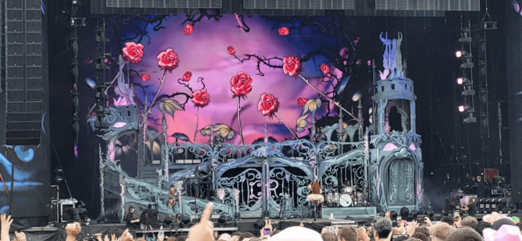 "Colorful concert stage with rose-themed backdrop and audience in foreground."