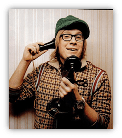 Man in vintage attire smiling while holding a classic telephone.