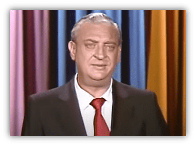 Rodney Dangerfield performing stand-up comedy on stage.