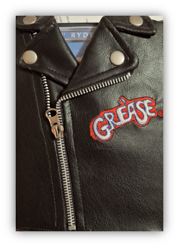 "Black leather jacket with 'Grease' logo and silver studs."