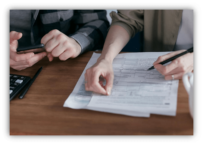 "Two people reviewing documents and making notes at a desk."