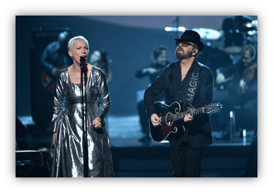"Annie Lennox and Dave Stewart perform on stage with a live band."