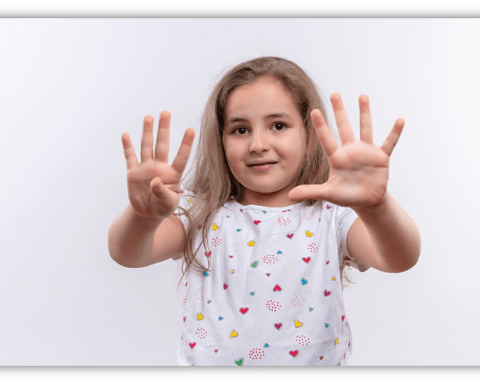 Young girl showing ten fingers, smiling against a white background.