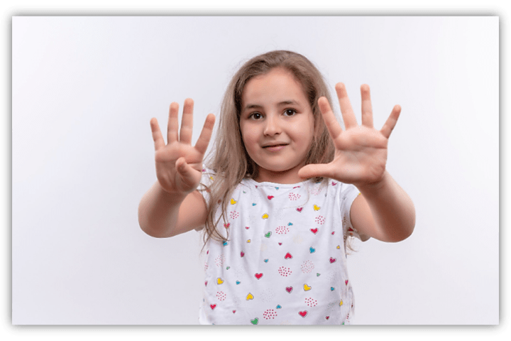 Young girl showing ten fingers, smiling against a white background.