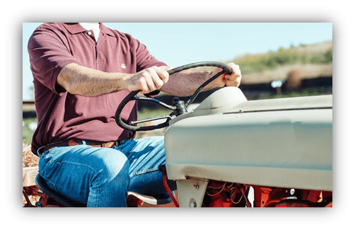 "Person driving a vintage tractor in a sunny field."
