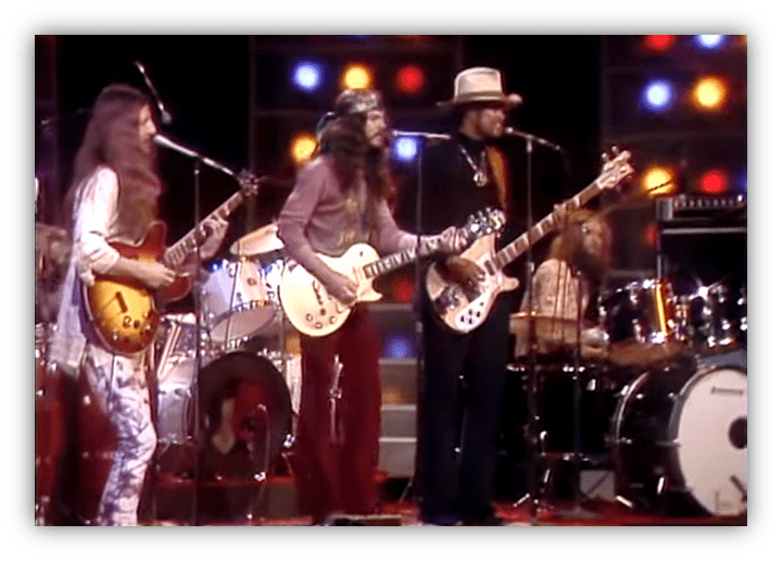 "Live band performance with guitarists and drummer on stage."