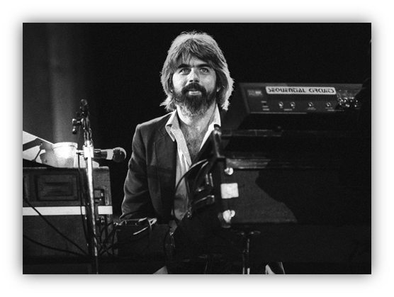 Musician performing on stage with a keyboard, black and white photo.