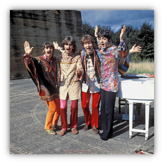 "Four musicians in colorful clothing joyfully posing outdoors near a piano."