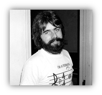 Black and white photo of a man with a beard wearing a humorous t-shirt.
