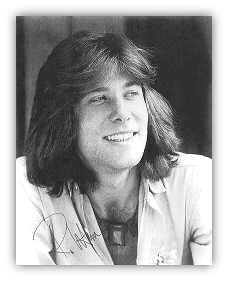 Black and white portrait of a smiling young man with long hair, featuring a signature.