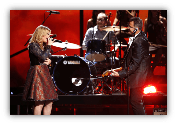 "Duet performance on stage with singer and guitarist, backed by a drummer."