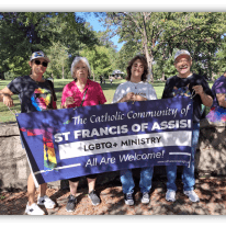 Four people holding a banner for St. Francis of Assisi LGBTQ+ Ministry, promoting inclusivity in a park setting.