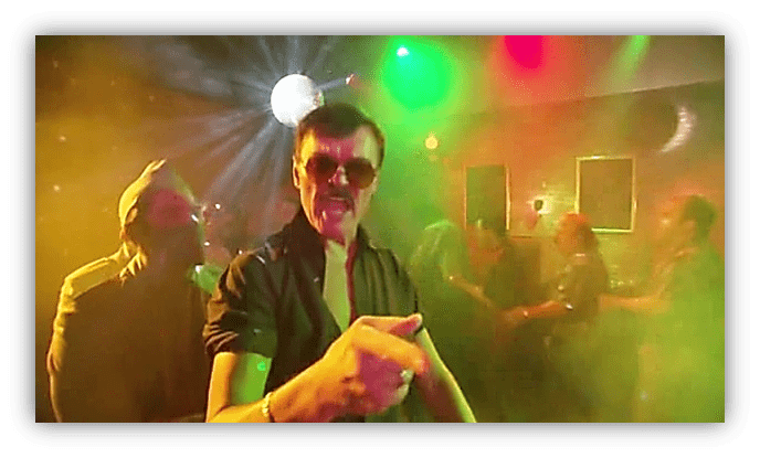"Man in sunglasses dancing at a vibrant disco party with colorful lights."