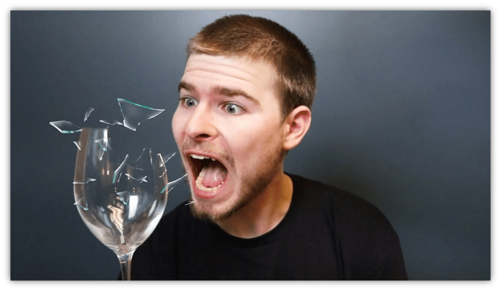 "Surprised man reacting to a shattering glass, with fragments flying."